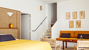 Chambre bien rangée avec lit confortable, canapé près des escaliers et portraits au-dessus.