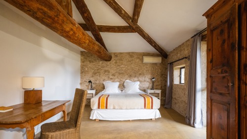 Chambre bien organisée avec lit, tables de chevet lampées et chaise placée à proximité.