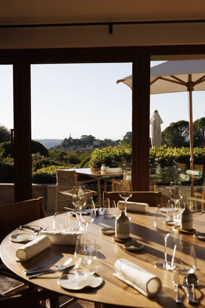 A well-appointed dining table at La Bastide restaurant in Provence, looking out onto a sun-drenched terrace and the surrounding countryside.