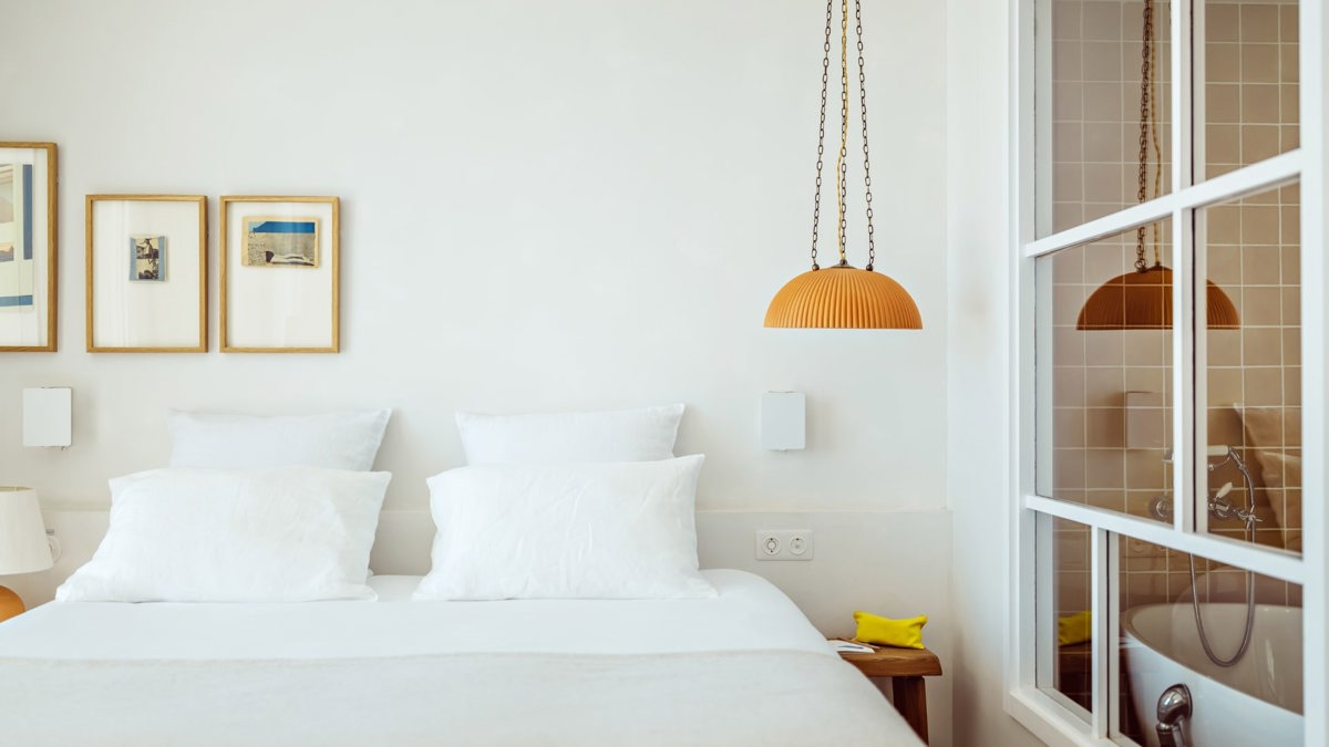 A well-organized bedroom features a cozy bed with beautifully mounted portraits above it.