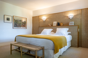 Une chambre bien organisée comprend un lit confortable avec deux portraits montés sur le mur de gauche.