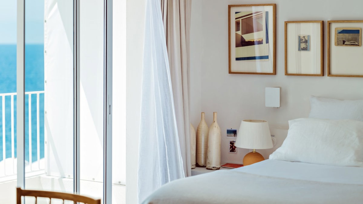 Some portraits are properly mounted above the bed, and a side table holds two bottles and a lamp.