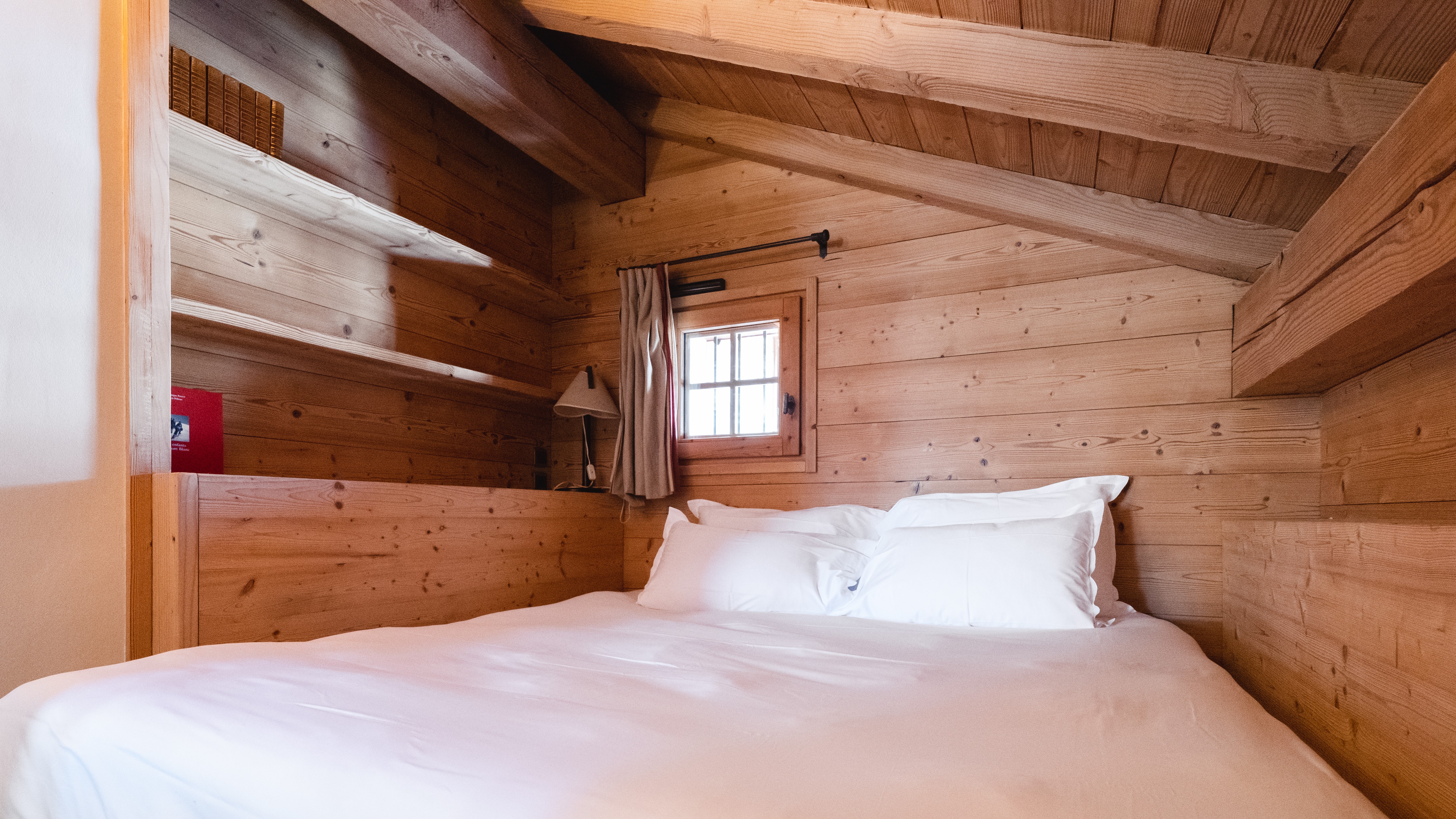 Cozy wooden bedroom with shelves and small window