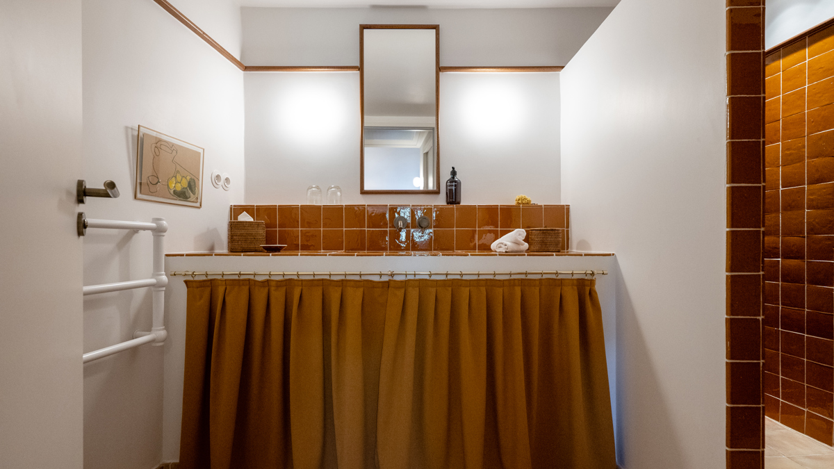 Une photo prise de la salle de bain montre un long miroir monté au-dessus du lavabo.