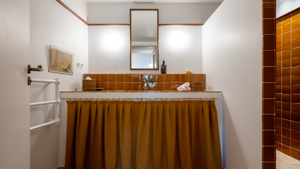 Une photo prise de la salle de bain montre un long miroir monté au-dessus du lavabo.