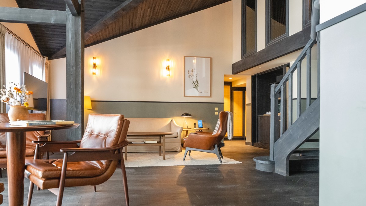 Un espace de vie comprend un canapé confortable installé près des escaliers, avec des portraits montés au-dessus.