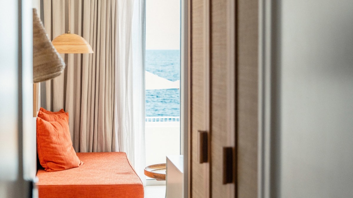 A chair is placed near the window, beautifully covered with flowing curtains.