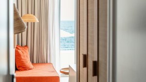 A chair is placed near the window, beautifully covered with flowing curtains.