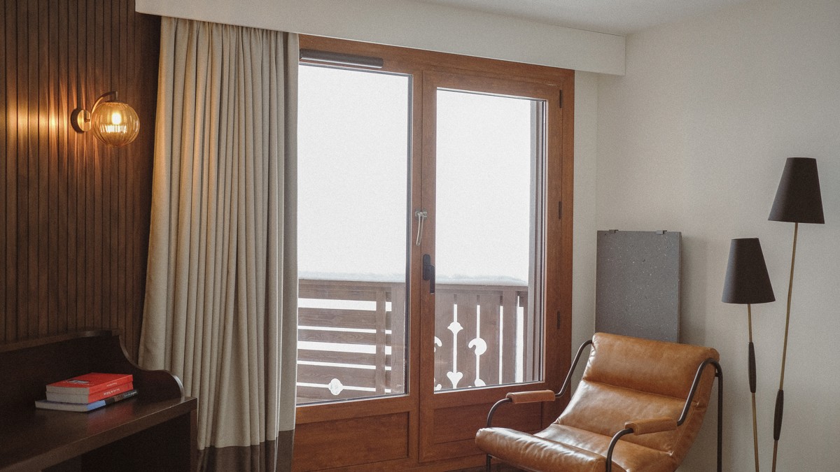 A cozy chair is placed near the glass door leading to a snowy balcony view.