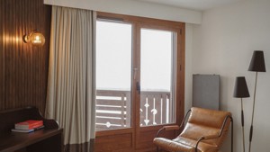 A cozy chair is placed near the glass door leading to a snowy balcony view.