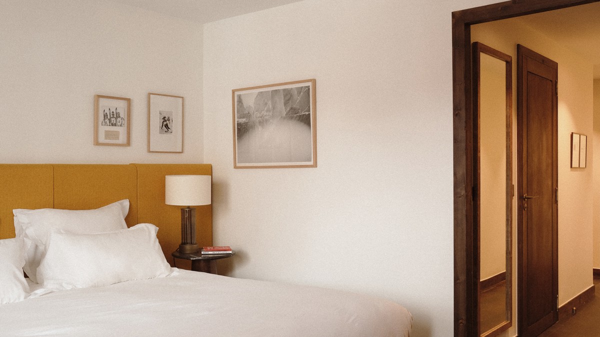 Three portraits are mounted on the wall above the side table holding a lamp.