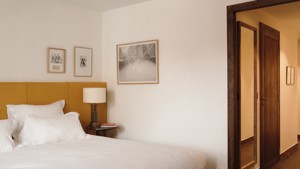 Three portraits are mounted on the wall above the side table holding a lamp.