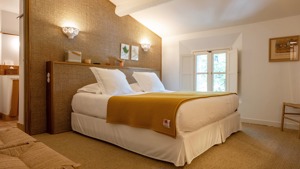 Une chambre bien organisée comprend un lit confortable avec un portrait monté sur le mur de droite.