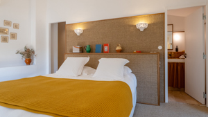 Une chambre bien organisée dispose d'un lit confortable avec quelques portraits montés sur le mur de gauche.