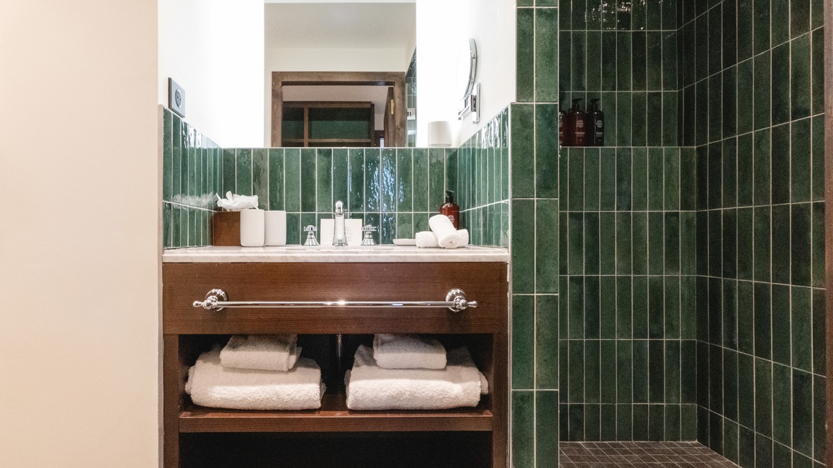 A photo captures a green-tiled bathroom with all essentials neatly organized and properly arranged.