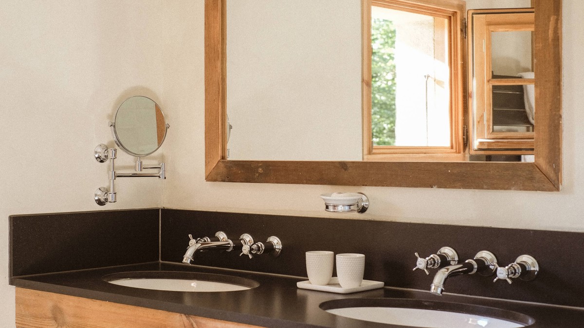 A rectangular mirror is mounted just above the washbasin countertop in the washroom.
