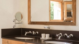 A rectangular mirror is mounted just above the washbasin countertop in the washroom.