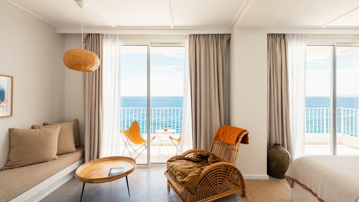 A cozy chair is placed near the glass window, offering a wonderful view of the ocean.
