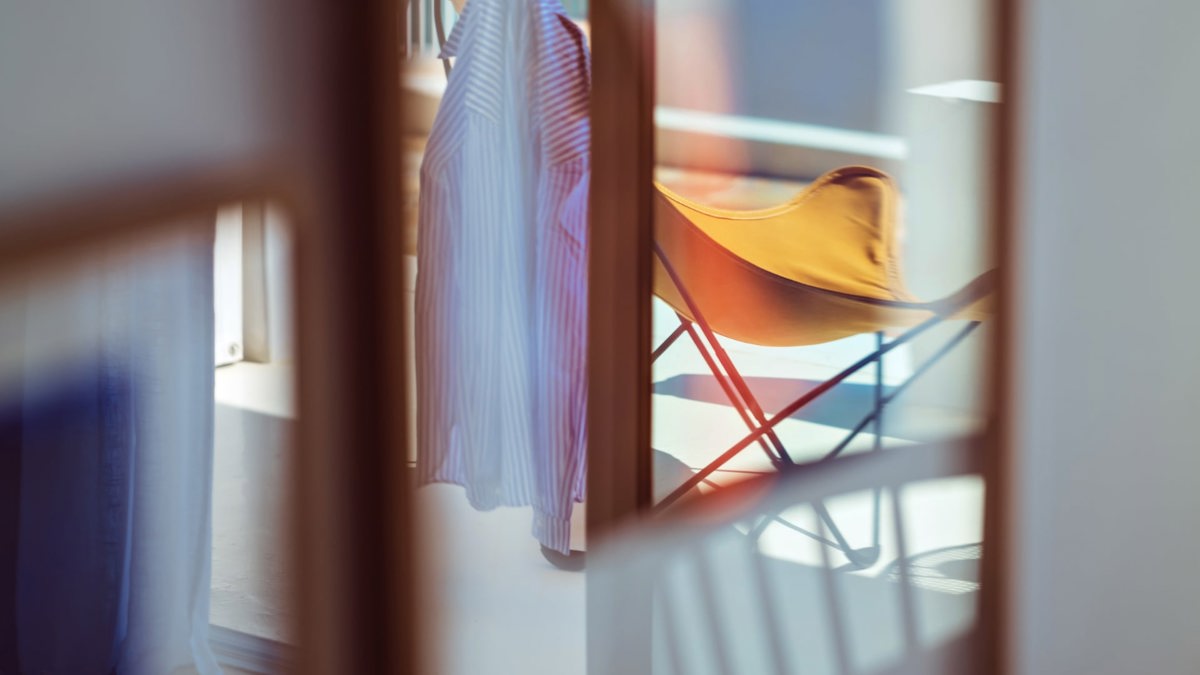 A shirt is hanging on a relaxing chair placed in the balcony area.