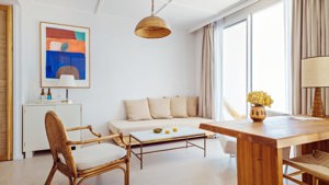 A set of cozy chairs is placed near the balcony door, with a portrait mounted above the table beside the sofa.