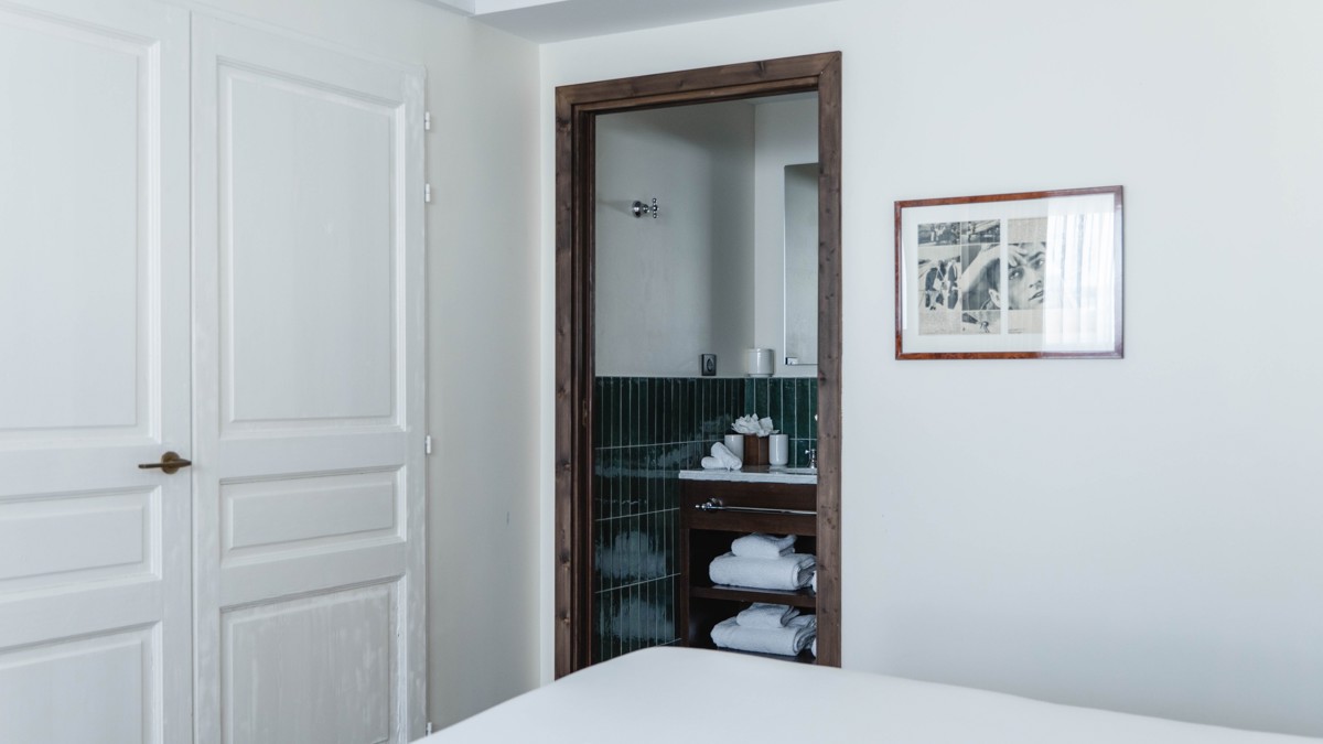 A neatly arranged towel rack is visible from the bedroom, with a portrait beside.