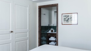 A neatly arranged towel rack is visible from the bedroom, with a portrait beside.