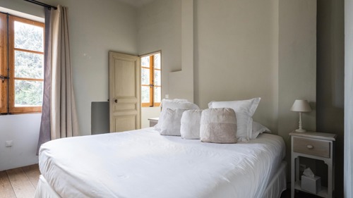 A tidy bedroom features a cozy bed with a side table holding a small lamp.