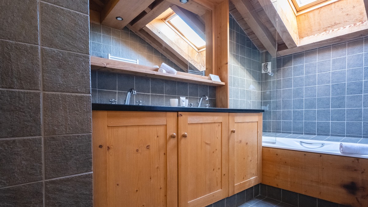 A clicked photo of the bathroom displays a bathtub on the right and washbasin on left.