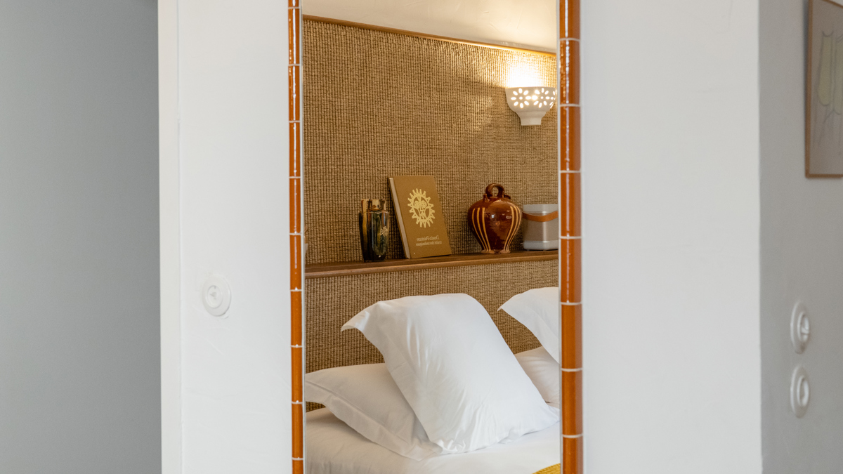 Le reflet d'un lit douillet avec un cahier sur la tête de lit apparaît dans le miroir.