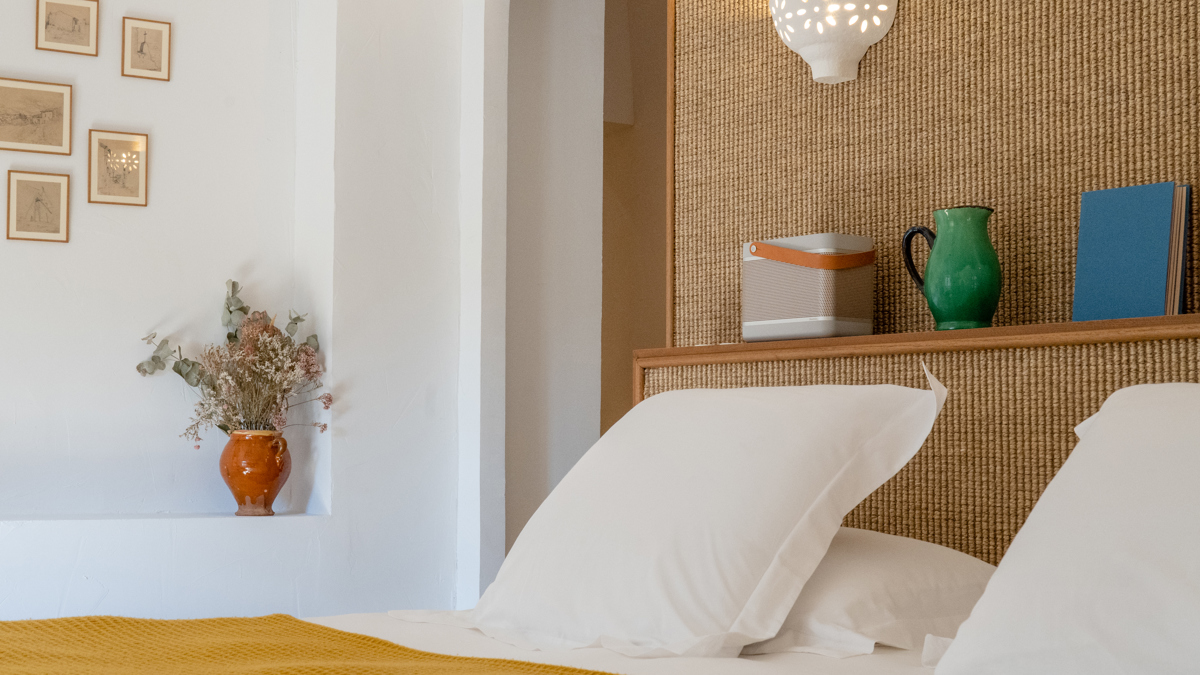 Objets décoratifs sur tête de lit et portraits accrochés sur le mur gauche.