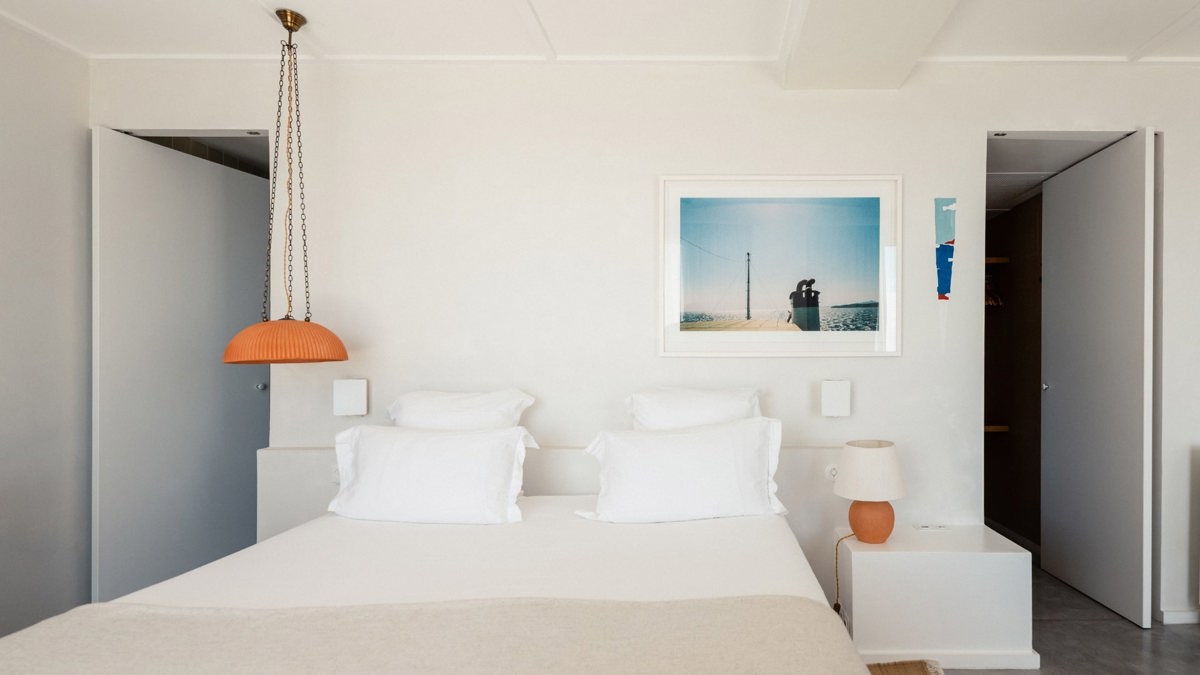 A well-organized bedroom showcases a cozy bed, a side table with a lamp, and portraits mounted above.