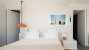 A well-organized bedroom showcases a cozy bed, a side table with a lamp, and portraits mounted above.