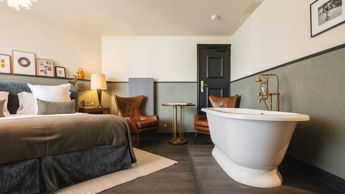 Une chambre bien organisée comprend un lit confortable et une baignoire placée près du mur de droite.