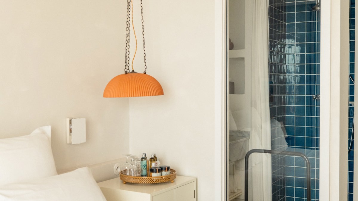 A hanging lamp is above the side table, with the green-tiled bathroom visible on the right.