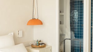 A hanging lamp is above the side table, with the green-tiled bathroom visible on the right.