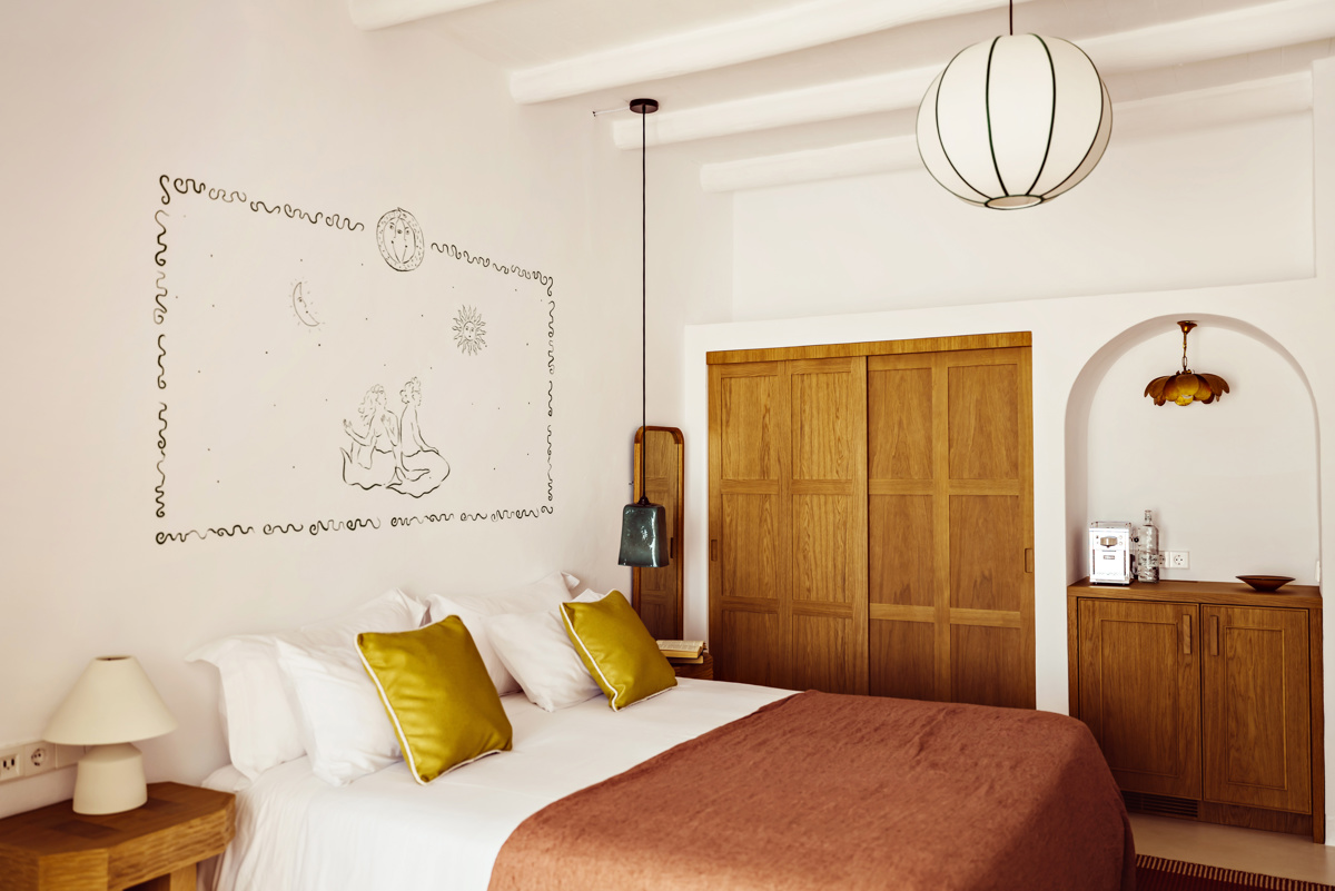 Chambre confortable avec placards en bois, décoration murale artistique, couverture rose et lumière naturelle venant de la fenêtre.