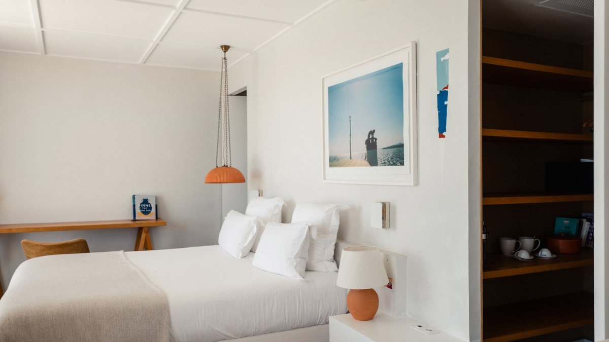 A well-organized bedroom features a cozy bed, portraits above the bed, and a notebook placed on the table.