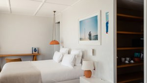 A well-organized bedroom features a cozy bed, portraits above the bed, and a notebook placed on the table.