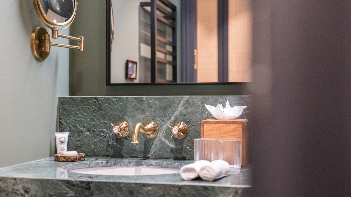 Salle de bains du Fitz Roy à Val Thorens, vasque en marbre vert, robinetterie laiton et miroir rétroéclairé