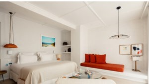 A well-organized bedroom features a cozy bed, a side table holding a lamp, and portraits mounted overhead.