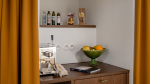 Ustensiles bien rangés sur étagères, corbeille de fruits et cafetière posées sur table.