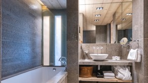 A clicked photo of a neat bathroom displays organized bathing essentials and a mirror above.