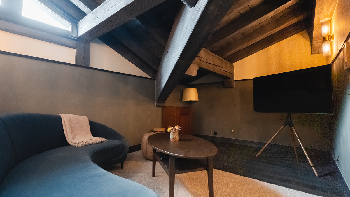 Une photo de l'espace de vie présente un canapé rond confortable, une table basse et une télévision.