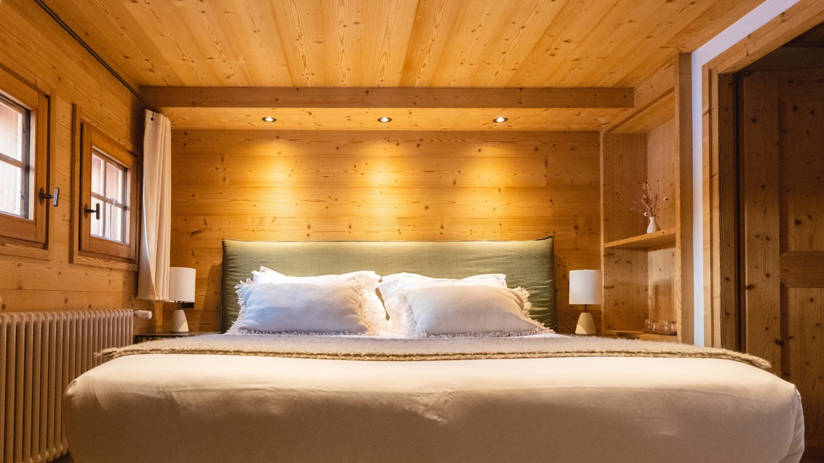 A cozy bed with feather-touch sheets, side tables with lamps, and dimly glowing lights.