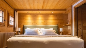 A cozy bed with feather-touch sheets, side tables with lamps, and dimly glowing lights.