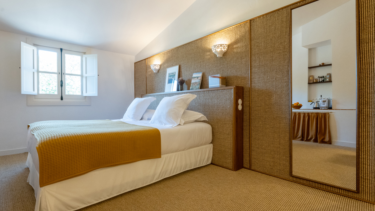 Une chambre bien rangée comprend un lit confortable avec un portrait placé au-dessus de la tête de lit.