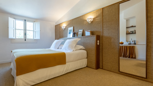 Une chambre bien rangée comprend un lit confortable avec un portrait placé au-dessus de la tête de lit.