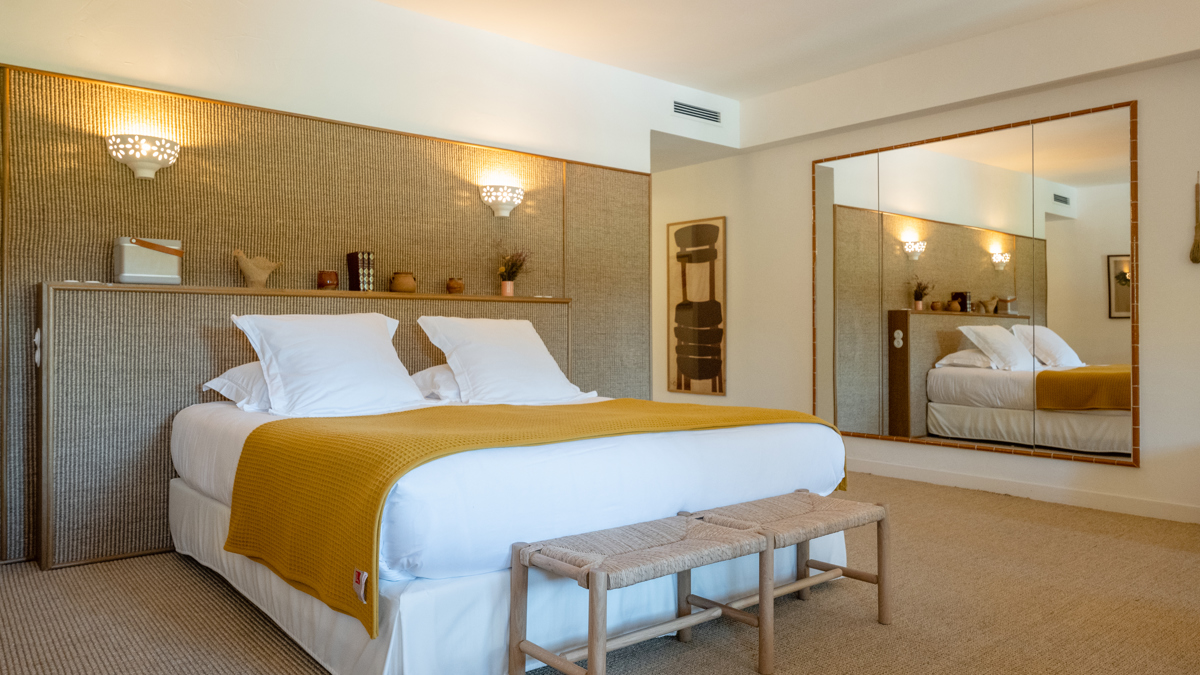 Une chambre bien organisée comprend un lit confortable avec des objets décoratifs placés sur la tête de lit.