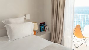 A bed’s side table is placed in the corner, holding a lamp and several notebooks.