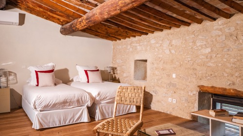 Chambre ordonnée avec deux lits confortables, tables de chevet lampées et chaise proche.